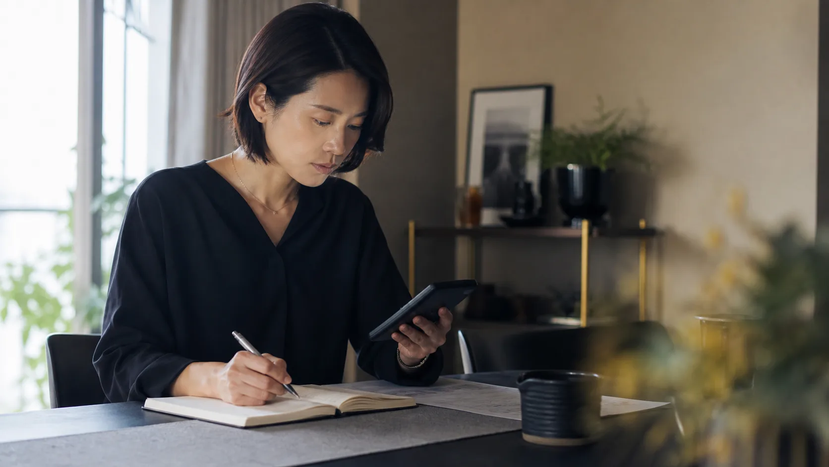電卓を手に、プランの金額をノートに書き比べているところ
